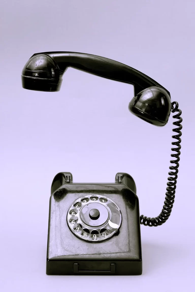 Černý telefon s otočným číselníkem se sluchátkem uchyceným nad základnou, zasazený na jednoduchém pozadí, připomínající starou uherské hradiště stomatologickou ordinaci.